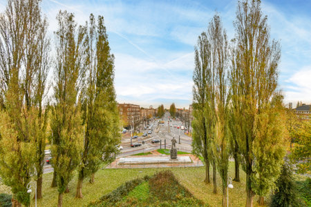 some trees in the middle of a city with blue sky and white clouds above them on a bright sunny dayのeditorial素材