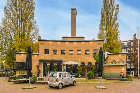 a car parked in front of a brick building with an umbrella on its roof and people walking byのeditorial素材