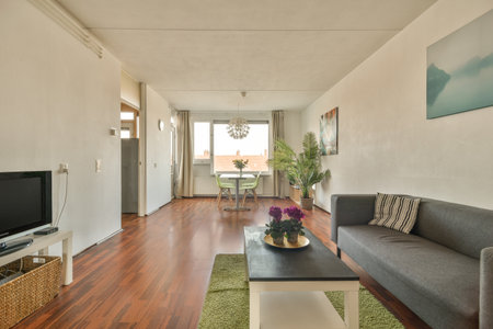 a living room with wood flooring and white walls, including a gray couch and coffee table in the cornerのeditorial素材