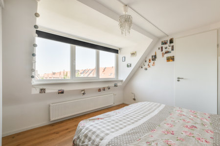 a bedroom with a bed, window and pictures hanging on the wall in front of the door to the roomのeditorial素材