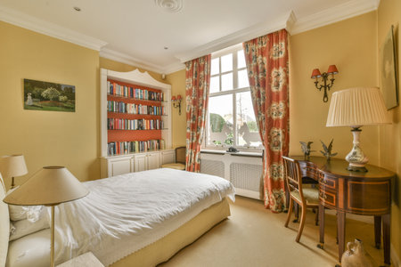 Amsterdam, Netherlands - 10 April, 2021: a bedroom with a bed, desk and books on the wall behind it...