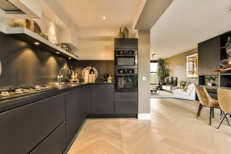 a modern kitchen with wood flooring and black cabinets in the center of the room is an open dining areaのeditorial素材