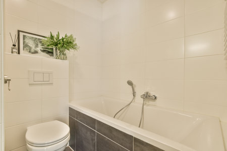 a bathroom with white tiles on the walls and black trim around the tub, toilet seat and shower head resterのeditorial素材