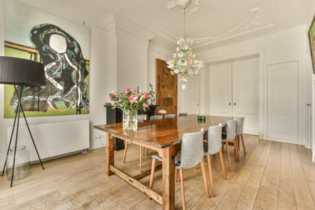 a woman sitting at a table with flowers in front of her and a lamp on the wall next to itのeditorial素材