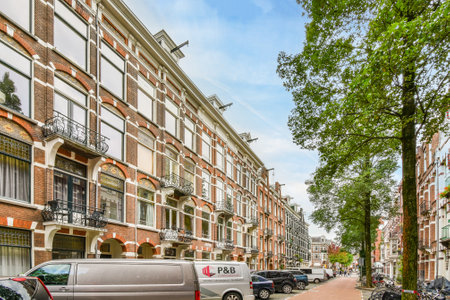 a city street with cars parked on the side and trees lining the sidewalks in front of buildings that are all lined upのeditorial素材
