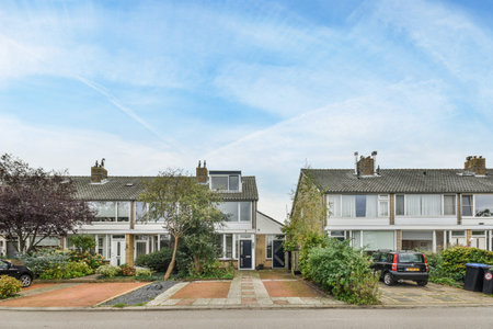 Amsterdam, Netherlands - 10 April, 2021: some houses with cars parked on the side of the road in front of them and people walking down the streetのeditorial素材