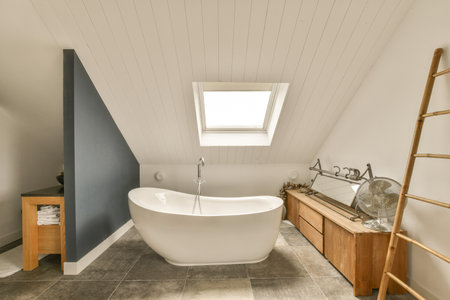 a bathroom with a skylight above the bathtub and wooden ladders on the wall next to the tubの写真素材