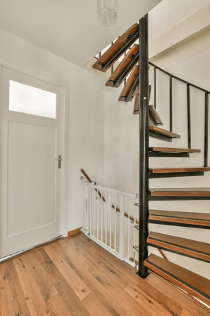 a staircase in a house with wood flooring and white walls on either side, there is an open door leading to the roomの写真素材