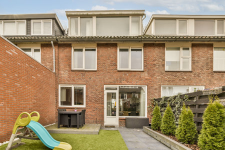 a brick house with a slide in the front yard and an outdoor play area for children to play outside...