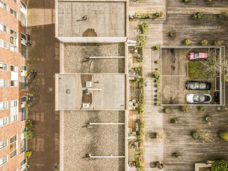 a parking lot with cars parked on the side and buildings in the back ground, taken from an aerial viewの写真素材