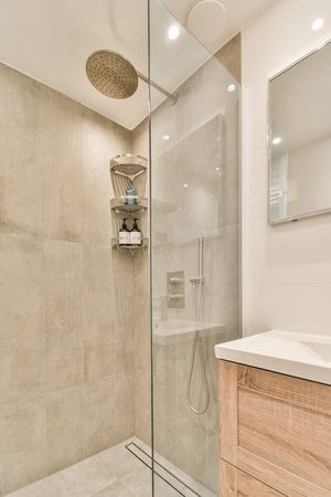 a bathroom with a glass shower door and wooden vanity in the corner next to the walk - in shower stallの写真素材