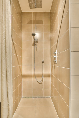 a walk in shower with beige tiled walls and white tiles on the wall behind it is an open shower stallの写真素材