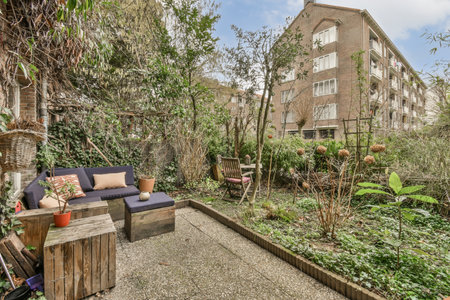 a backyard area with lots of plants and flowers on the ground in front of an apartment building,...