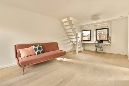 a living room with a pink couch and stairs leading up to the top floor in front of the staircasesの写真素材