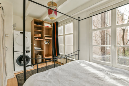 a bedroom with a bed, cabinets and a window that looks out onto the street in front of the room