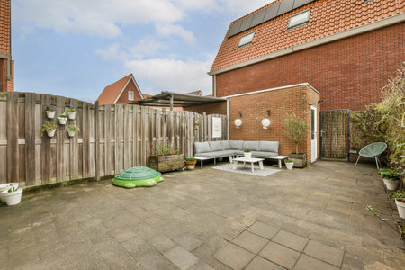a backyard area with a couch, chair and other items on the ground in front of a brick wall that has...