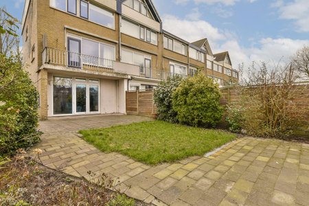 an outside view of a house with some plants in the yard and bushes growing on the side of the...