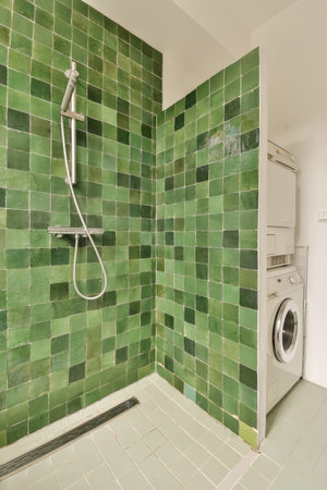 a green tiled bathroom with a washing machine and washer in the corner, which is also used as a...