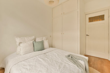 a bedroom with a bed and closets in the wall behind it is an open door that leads to another room