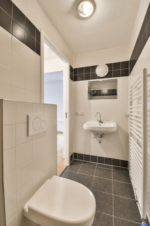 a bathroom with black and white tiles on the walls, floor, and toilet in its corner area