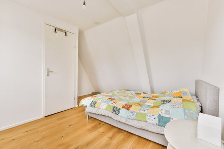 a bed in a room with white walls and wood flooring on one side, there is an open door to the other...