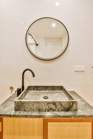 a bathroom with marble counter top and wooden cabinet under the sink is round mirror on the wall in...