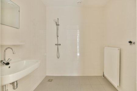 a bathroom with white tile flooring and wall mounted shower mixers in the corner of the bathtub is next to the sinkの写真素材