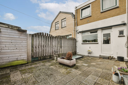 a backyard area with a wooden fence and potted planters on the ground in front of a brick building