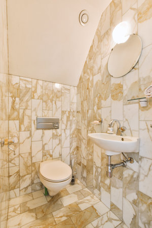 a bathroom with marble tiles on the walls, and a white toilet in the corner next to the shower stallの写真素材