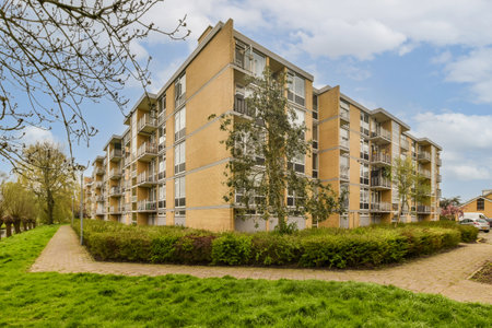 an apartment complex with green grass and trees in the foreground, on a bright sunny day - stock photoの写真素材