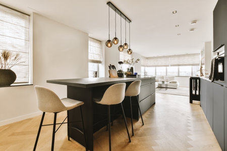 a kitchen and dining area in a modern home with wood flooring, white walls, black cabinets and large windowsの写真素材