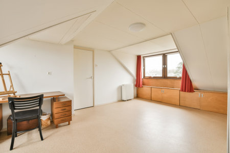 a room with a desk, chair and window in the corner to the right is an open door that leads to another roomの写真素材