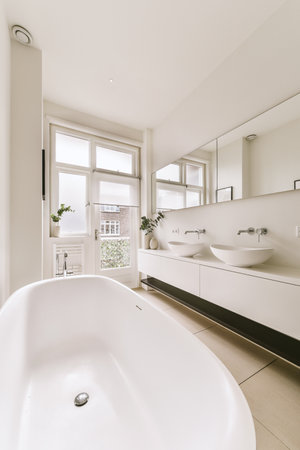 a bathroom with a large bathtub in the middle and two sinks on the other side, there is a window to...
