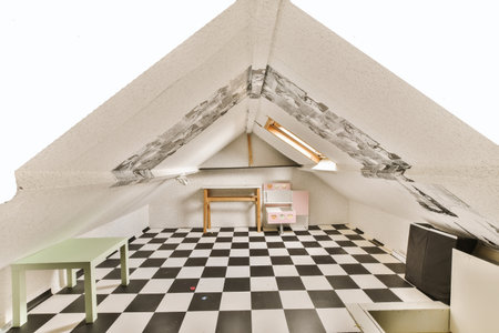 a room with black and white checkered tiles on the floor in an attic - like space that has been used for many yearsの写真素材