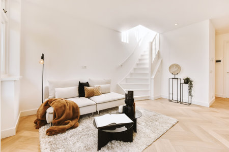 a living room with white walls and hardwood flooring, there is a teddy bear sitting on the rug in front of the couchの写真素材