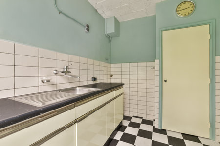 a kitchen with black and white tiles on the floor, including a clock in the wall to the left sideの写真素材