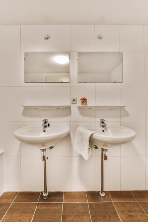 a bathroom with two sinks and one is in the middle of the photo, its white tiles on the wallの写真素材