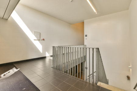 an empty room with stairs leading up to the second floor and light coming in through the window on the right sideの写真素材