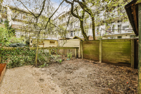 a backyard area with some trees and bushes in the foreground, taken from an angle on a sunny day