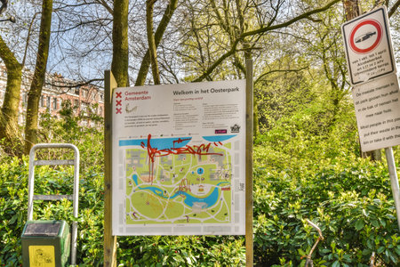 some signs in the middle of a park with trees and bushes on either sides there is a sign that says...