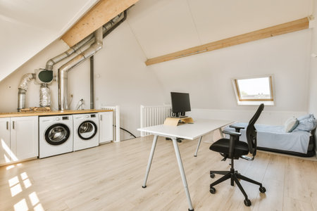 a laundry room with a washer and dryer in the corner, next to an office desk on the right sideの写真素材
