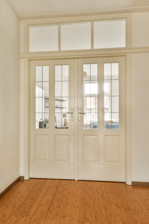 an empty room with wooden floors and white walls, two doors are open to reveal the view from the outsideの写真素材