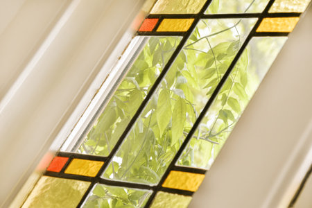 a stained glass window with green leaves on it and an orange flower in the bottom right hand corner...