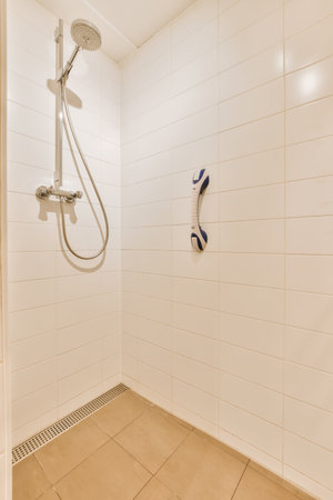 a shower room with tile flooring and white tiles on the walls, there is a blue hand held in front of...