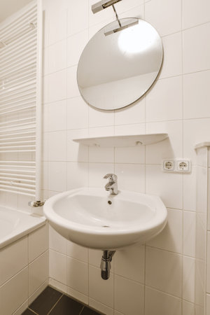 a bathroom with white tiles and black tile on the wall behind it is a sink, mirror and towel rack