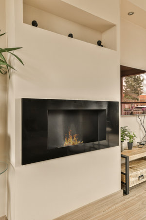 a modern living room with wood flooring and a fireplace in the middle part of the room is bright whiteの写真素材