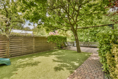 a backyard with a green lawn and wooden fenced in to the back yard there is a blue toy car parked on...