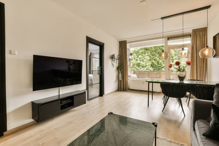 a living room with wood flooring and large windows looking out onto the garden outside, there is a...