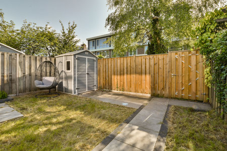 a backyard area with a swing in the middle part of the yard, and a wooden fence that is behind it