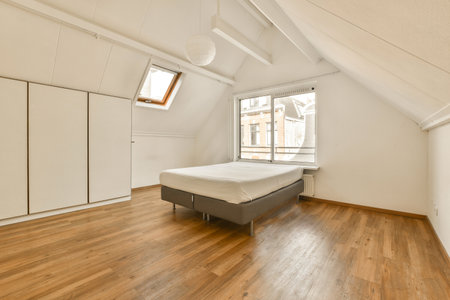 a bedroom with wood flooring and white walls in an attic - style apartment, which has been used for...